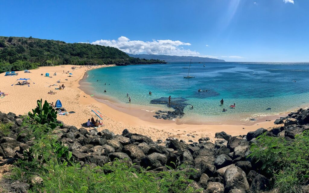 Waimea Bay's sandy beach and calm summer water on Oahu's North Shore