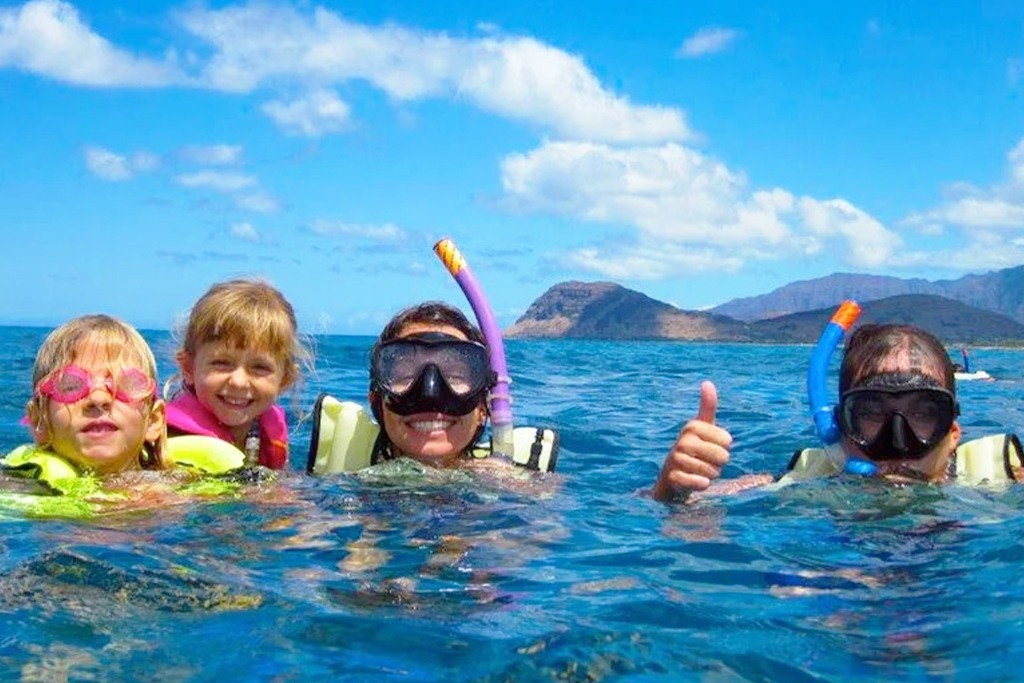 A family snorkeling together in clear water off Oahu