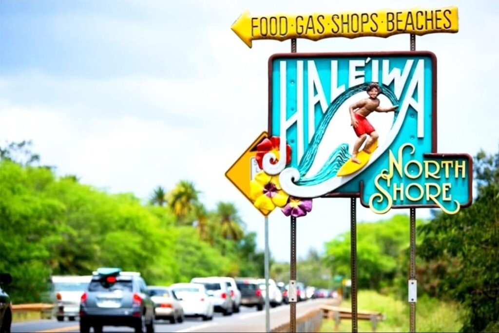 Traffic on Kamehameha Highway passing the Haleiwa North Shore sign