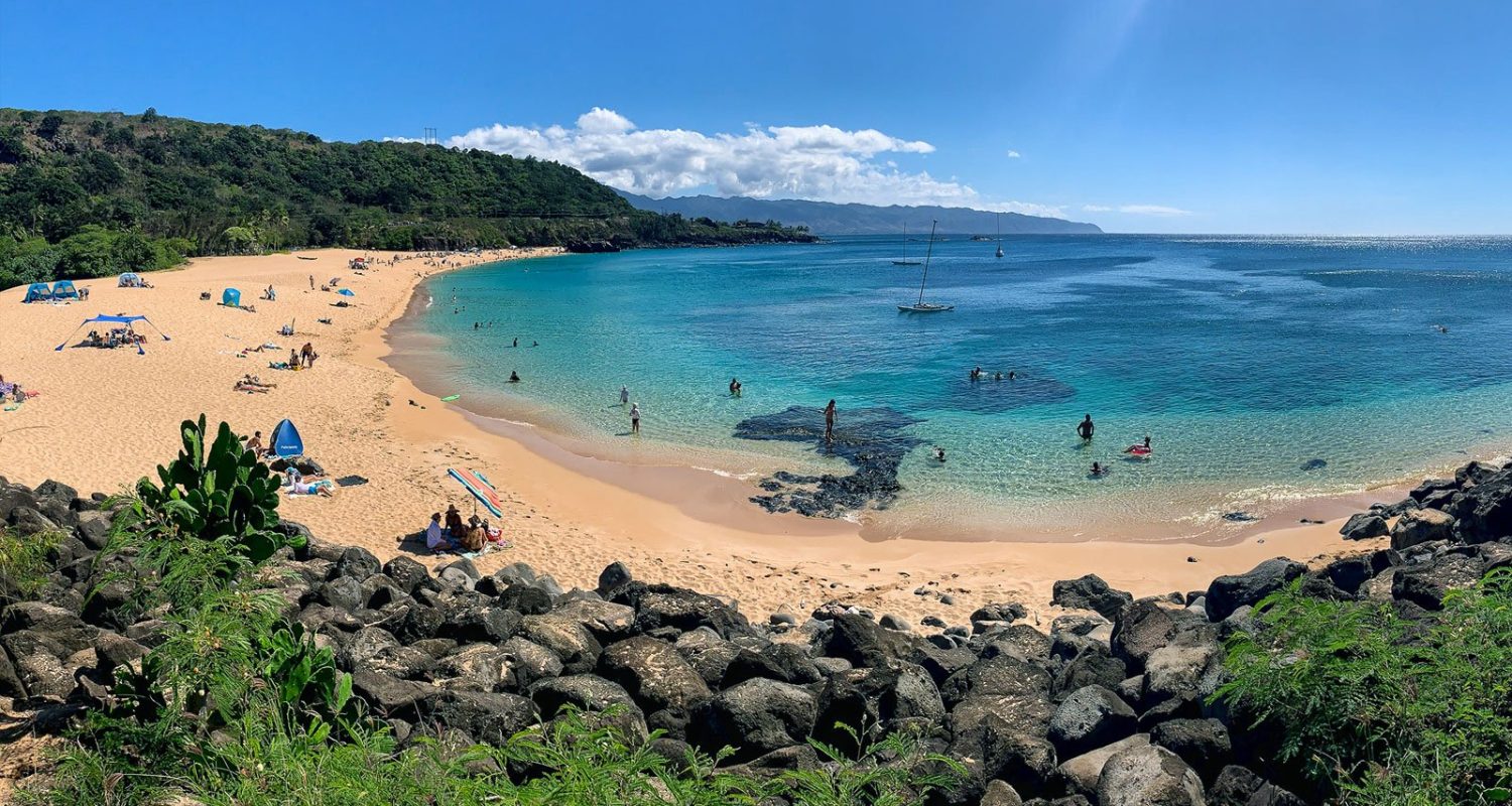 Waimea Bay's sandy beach and calm summer water on Oahu's North Shore