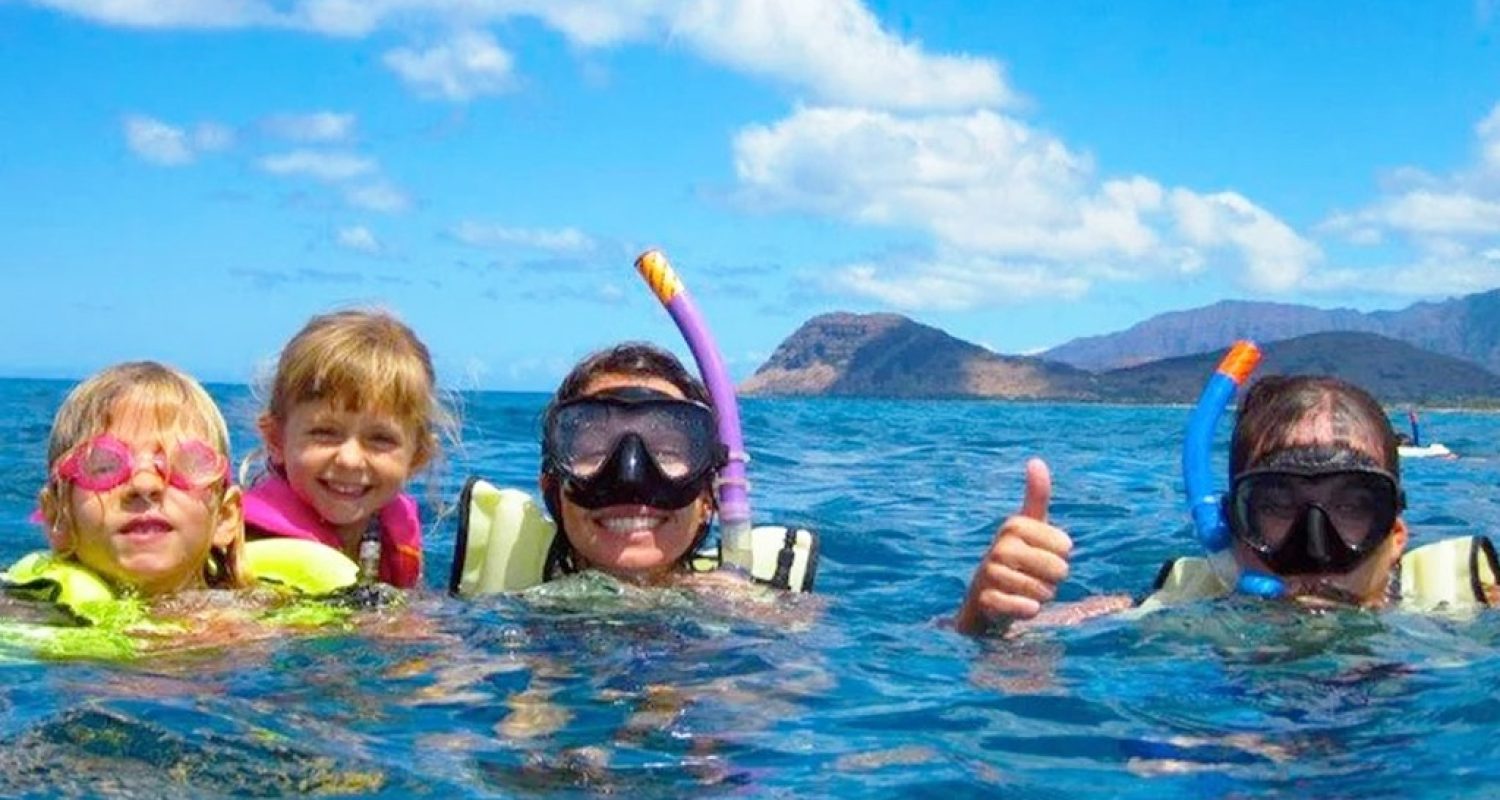A family snorkeling together in clear water off Oahu