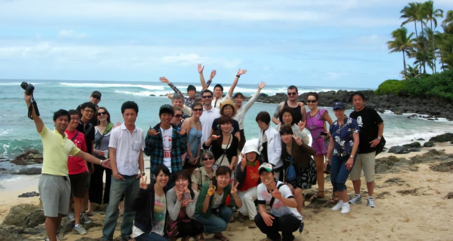 A tour group celebrating on a rocky beach on Oahu