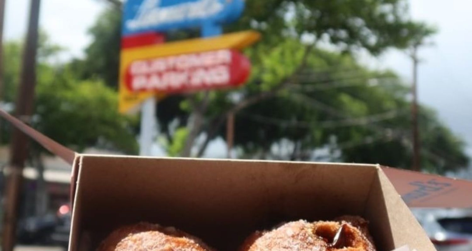 A box of Leonard's Bakery malasadas in front of the bakery sign